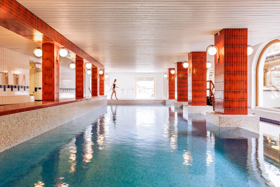 Long rectangular indoor pool at Altein, Arosa, with tiled pillars and sconce lighting