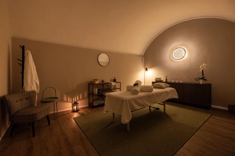 Softly lit treatment room with massage table and rolled towels at Altein, Arosa