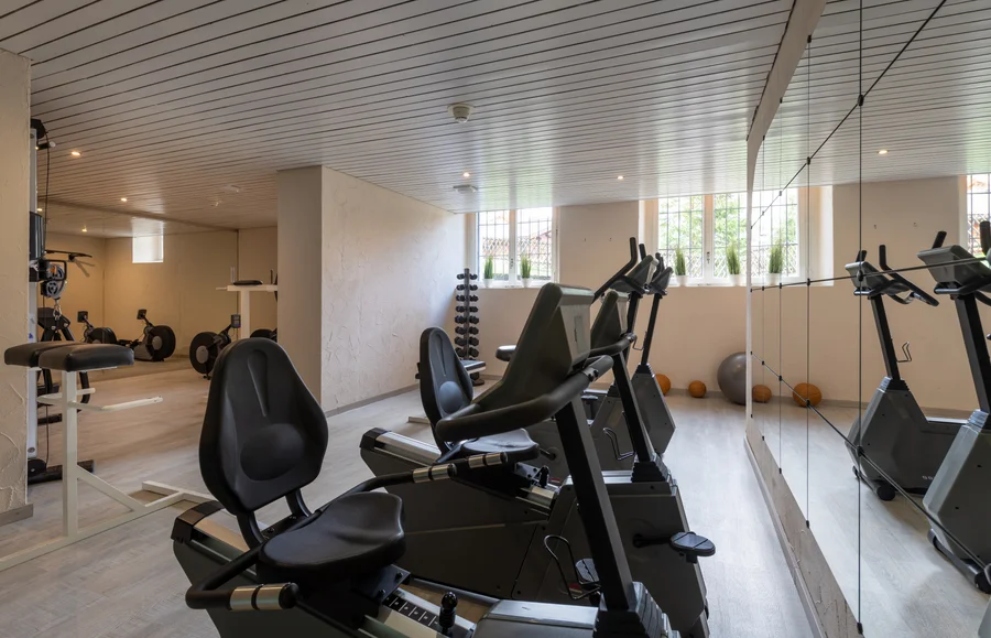 Fitness room with cardio machines and mirrored wall at Altein, Arosa