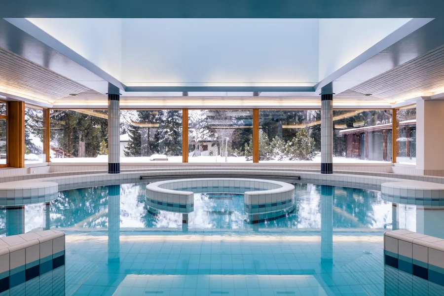 Indoor pool with panoramic windows onto snow covered pines at Altein, Arosa