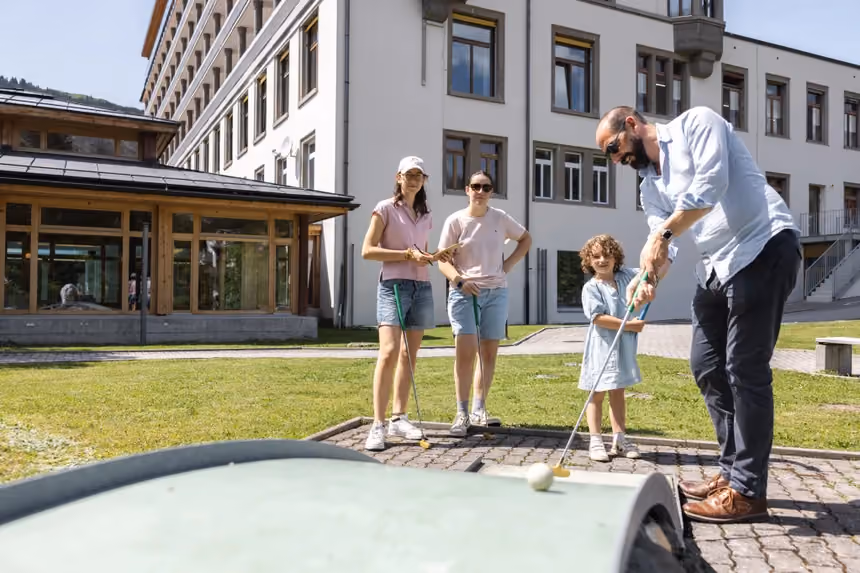 A family playing mini golf beside the hotel at Altein, Arosa