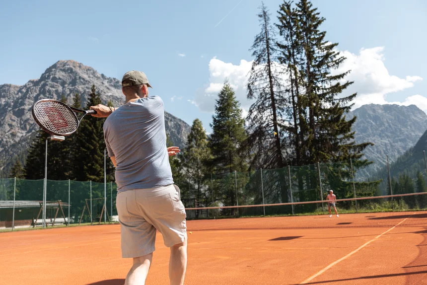 A guest playing on the outdoor clay tennis court at Altein, Arosa