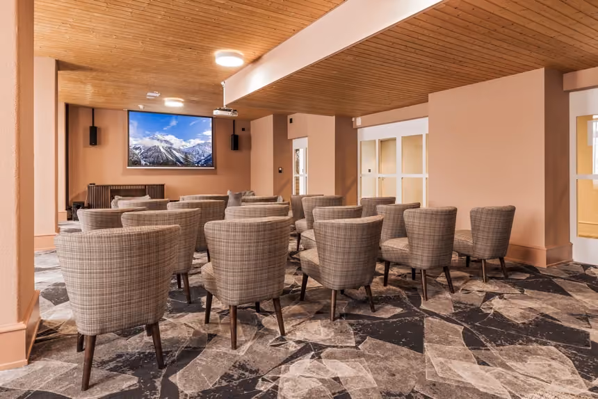 The cinema room at Altein, Arosa, with rows of plaid armchairs facing the screen