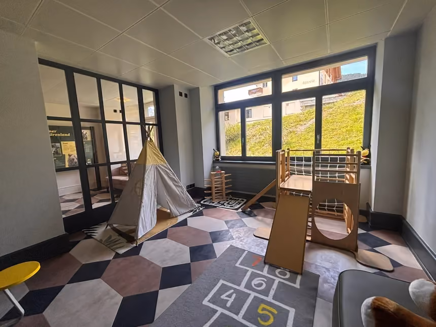 The kids play room at Altein, Arosa, with a teepee, climbing frame and hopscotch rug by the windows