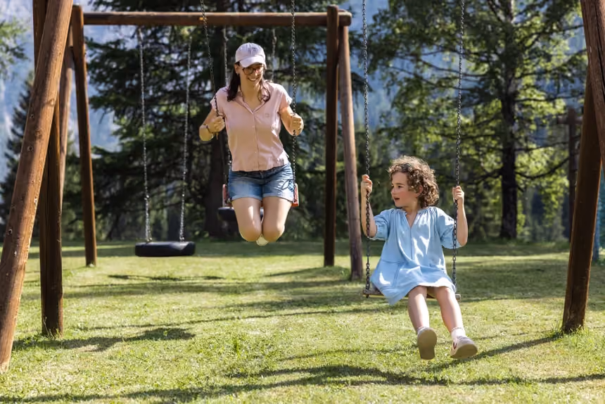 A mother and child on the swings in the garden playground at Altein, Arosa