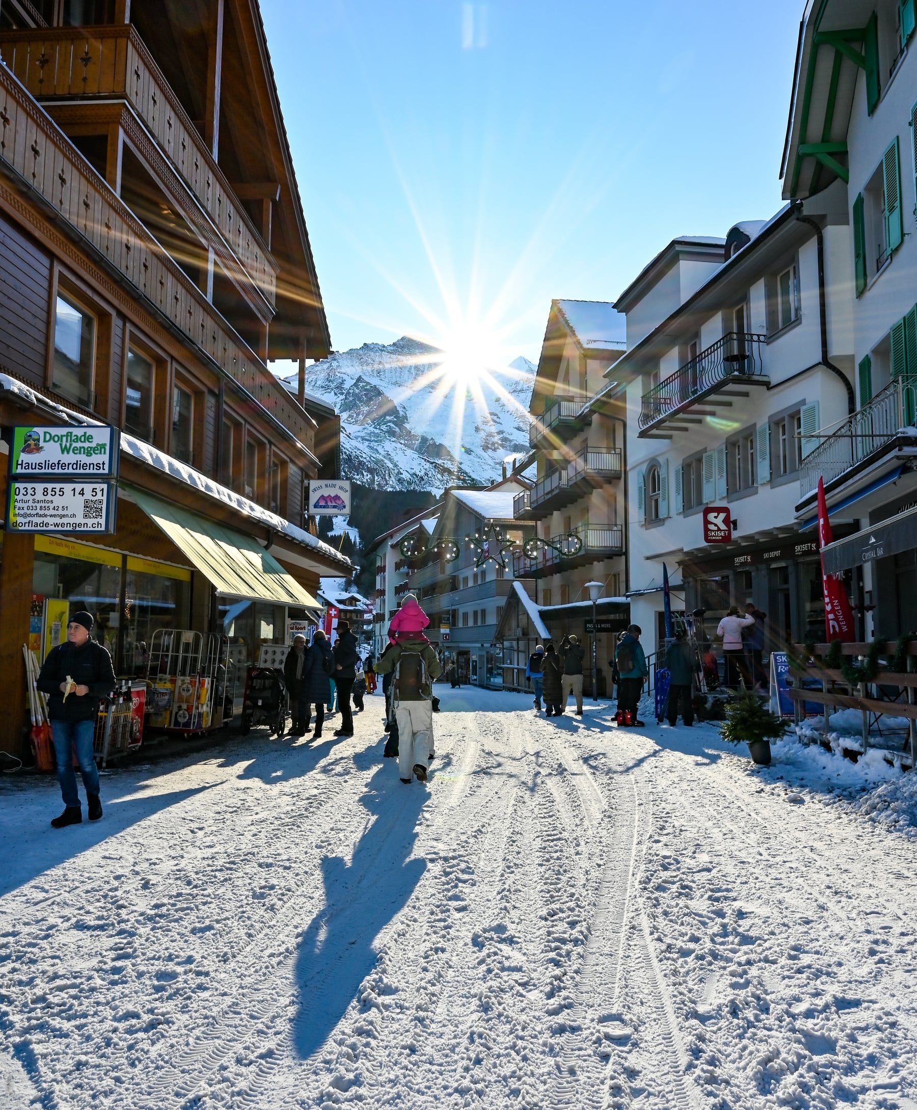 The Dorfstrasse in Wengen under snow, with people walking down the middle of the car-free street