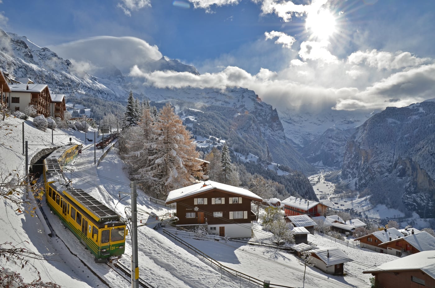 The yellow and green Wengernalp cog railway descending towards Wengen above the Lauterbrunnen valley