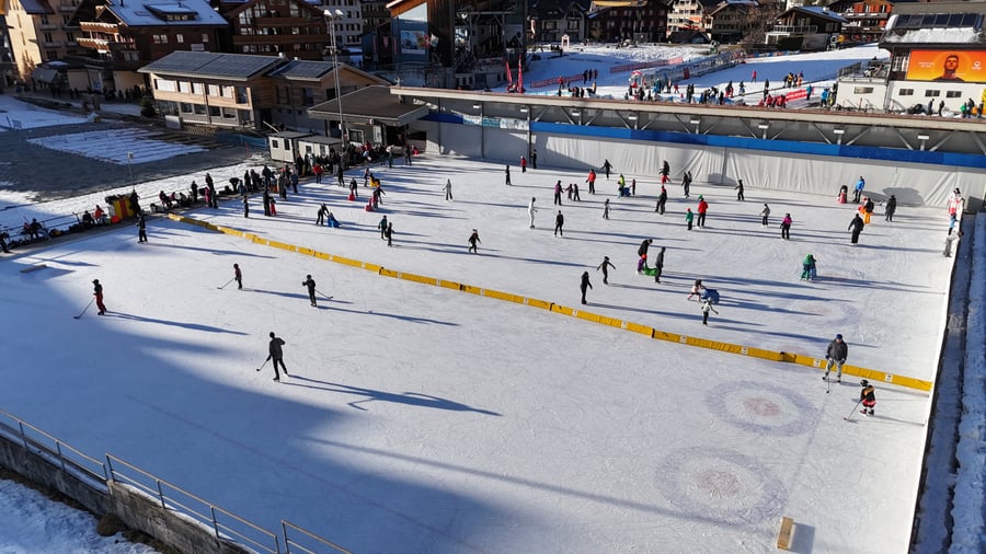 Skaters and curling sheets on the open-air ice field in the centre of Wengen