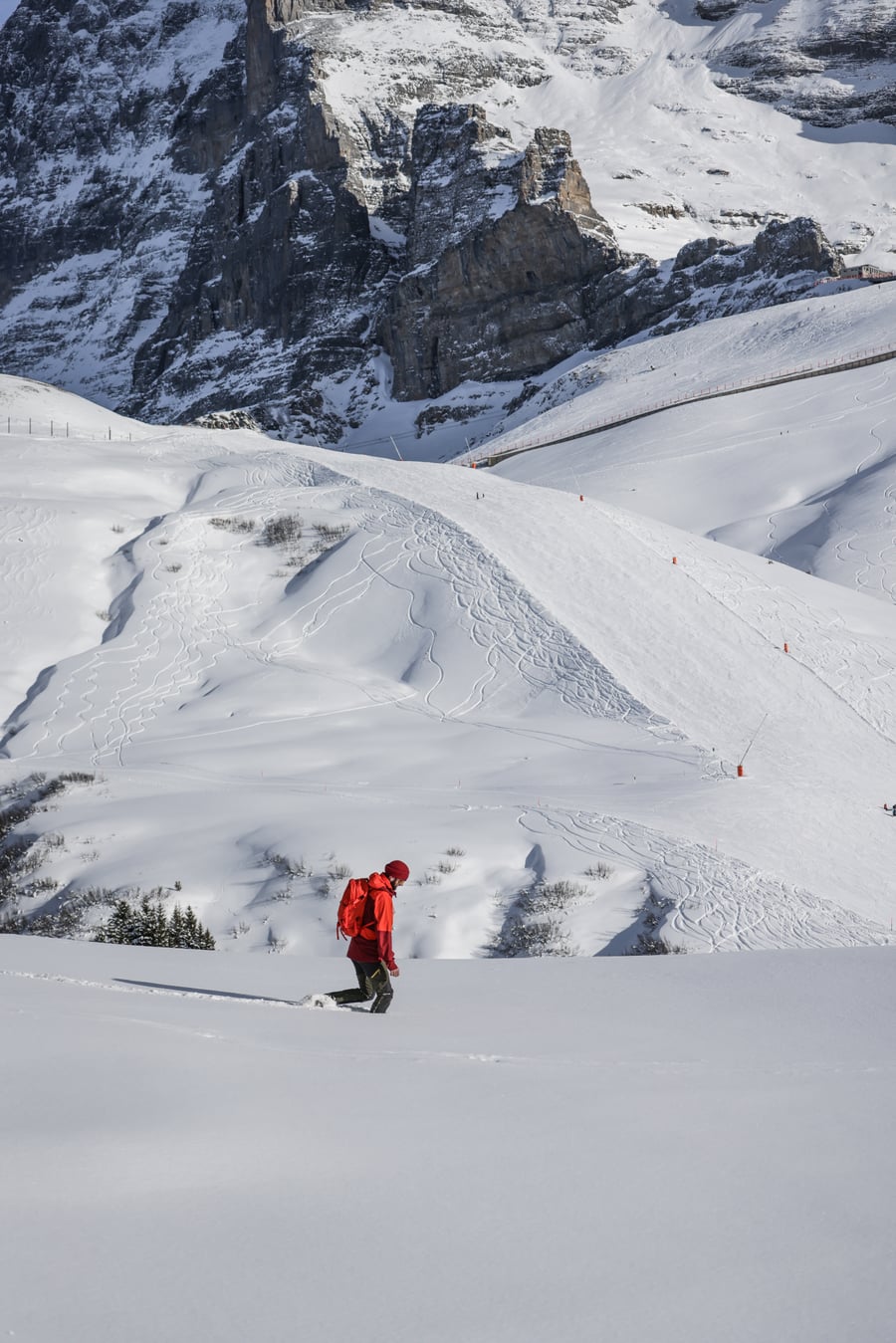 A walker crossing deep snow on a high open slope in the Jungfrau region