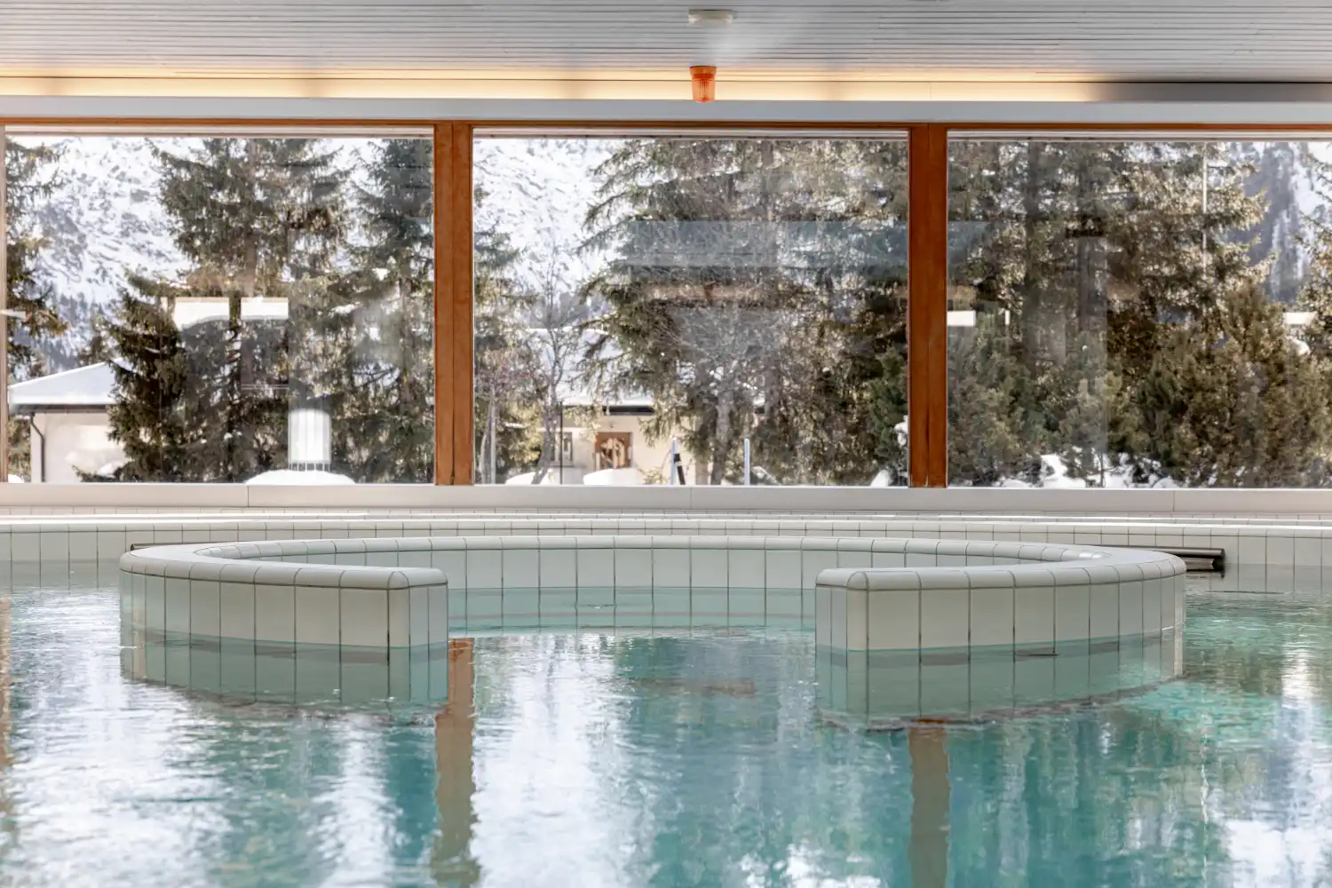 Indoor pool and whirlpool at Altein with snow outside the windows