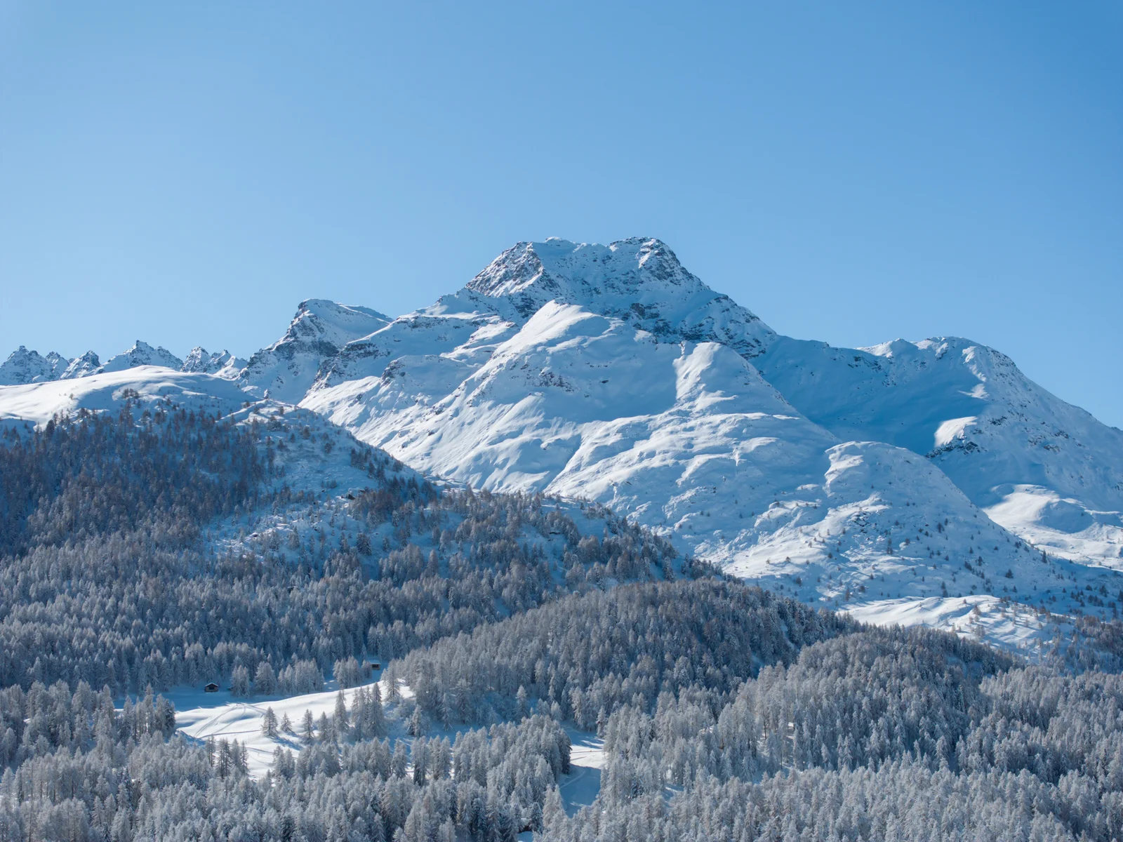 Snow-covered Engadin mountains under a blue sky