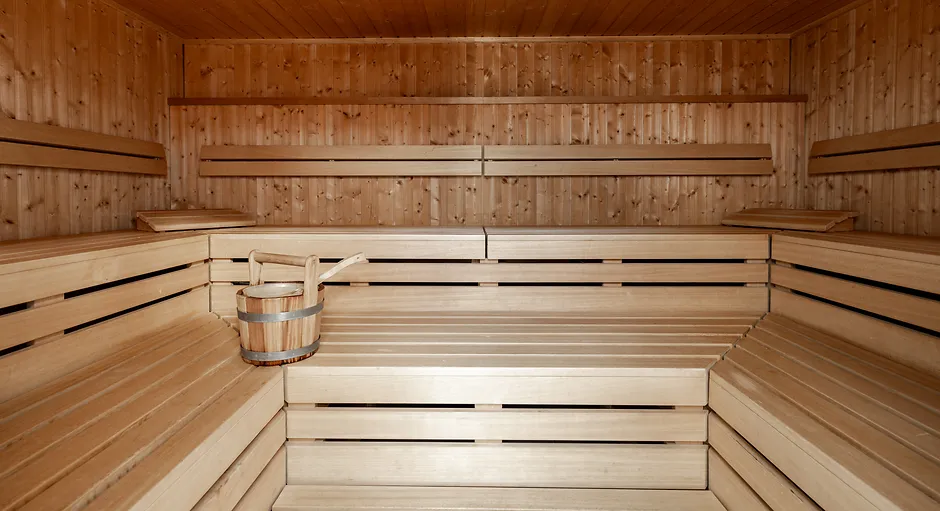 Empty wooden sauna interior with tiered benches and a wooden bucket with ladle.