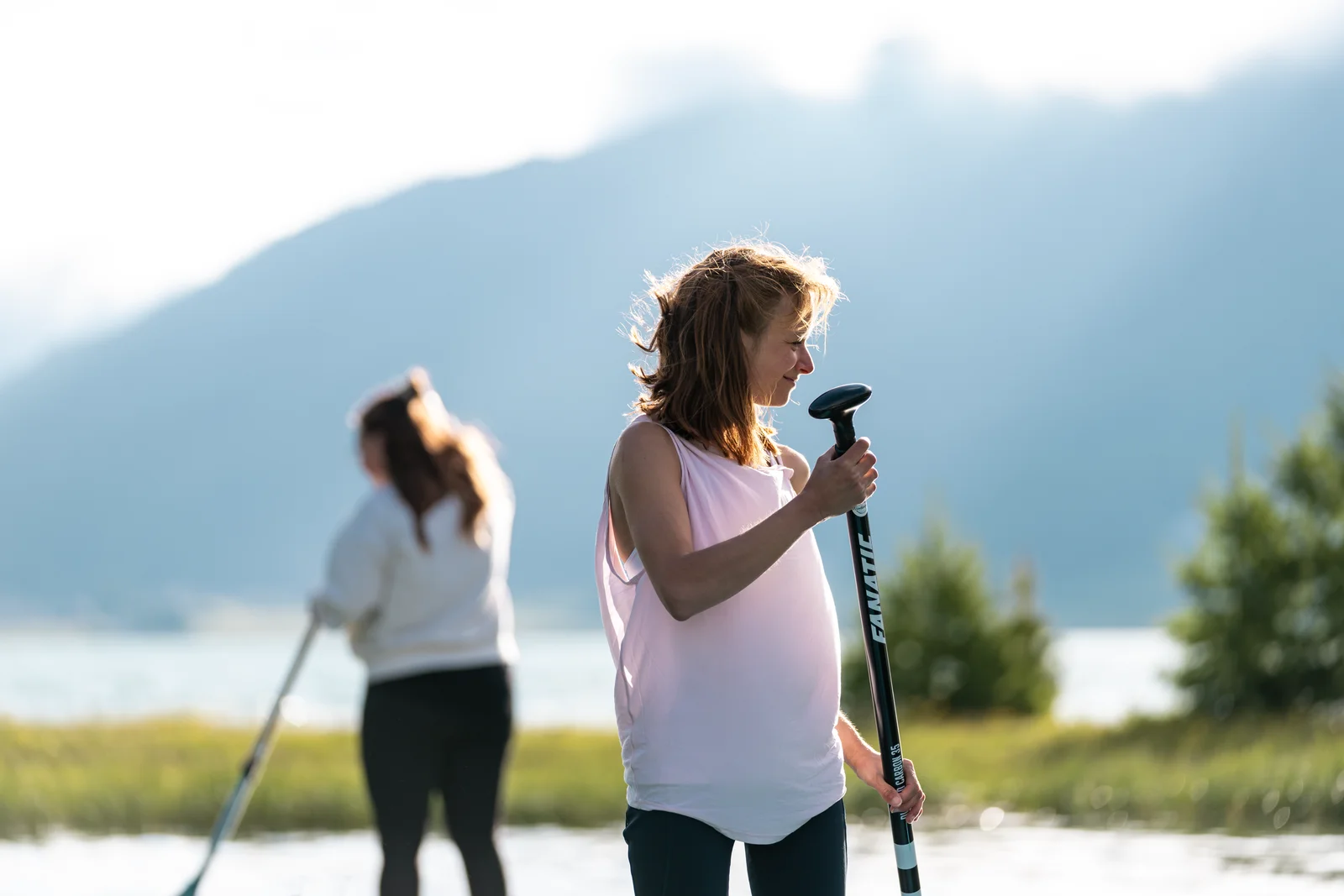 Deux adeptes du stand up paddle sur un lac calme près de Sils Maria avec des montagnes voilées de brume en arrière-plan
