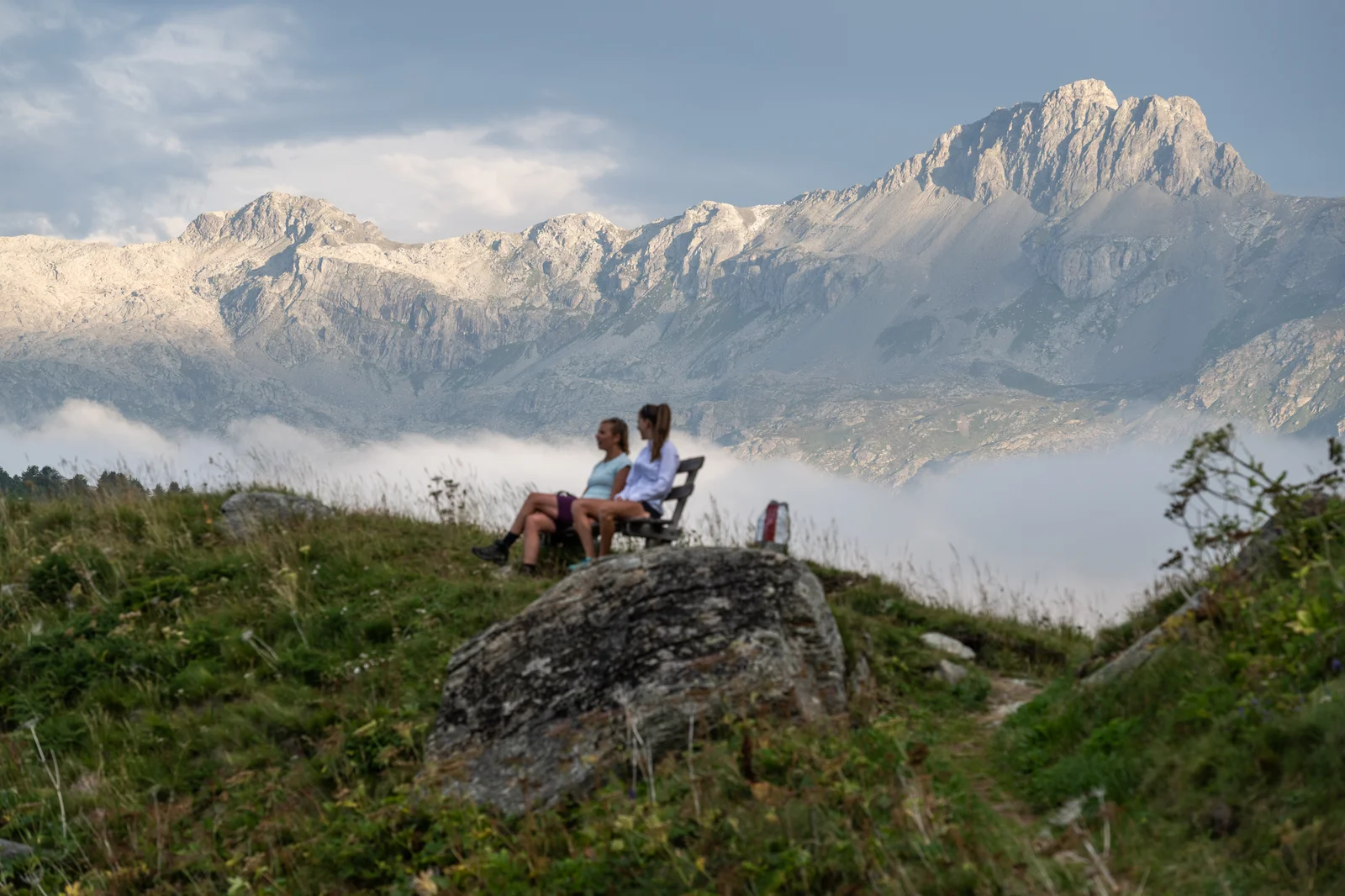 Randonneurs sur la rive du lac de Sils en été avec des forêts de mélèzes et les montagnes de l'Engadine