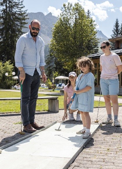 Paar beim Minigolf im Altein, Arosa, mit den Aroser Bergen und blauem Himmel im Hintergrund