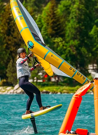 Wing foiler riding across a turquoise Engadine lake at the Engadinwind festival