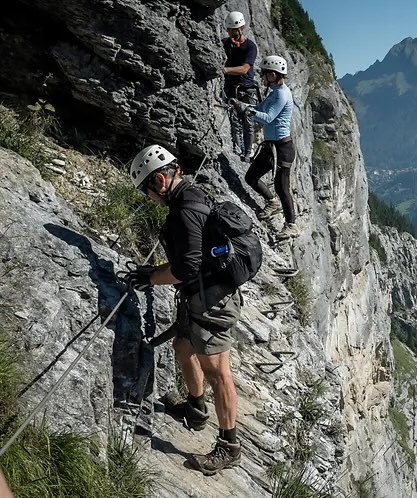 Climber secured to the steel cable of a via ferrata rock face above Arosa.