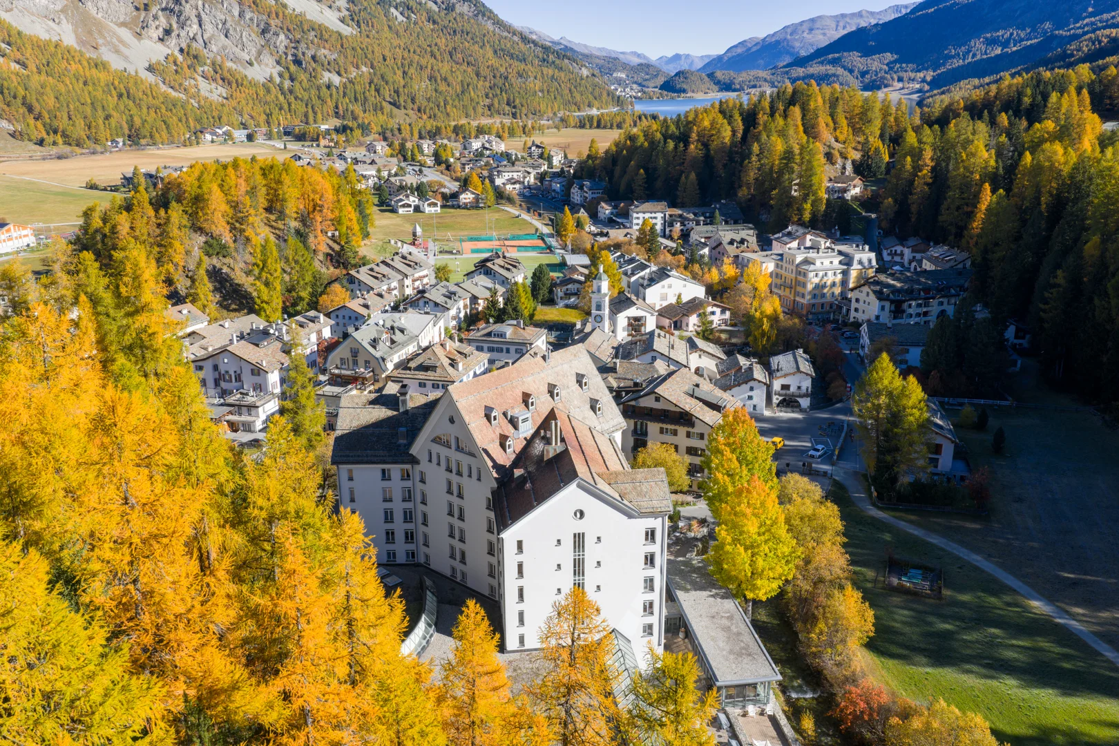 Le village de Sils Maria en Engadine cerné de mélèzes dorés en automne, avec le lac de Sils au-delà