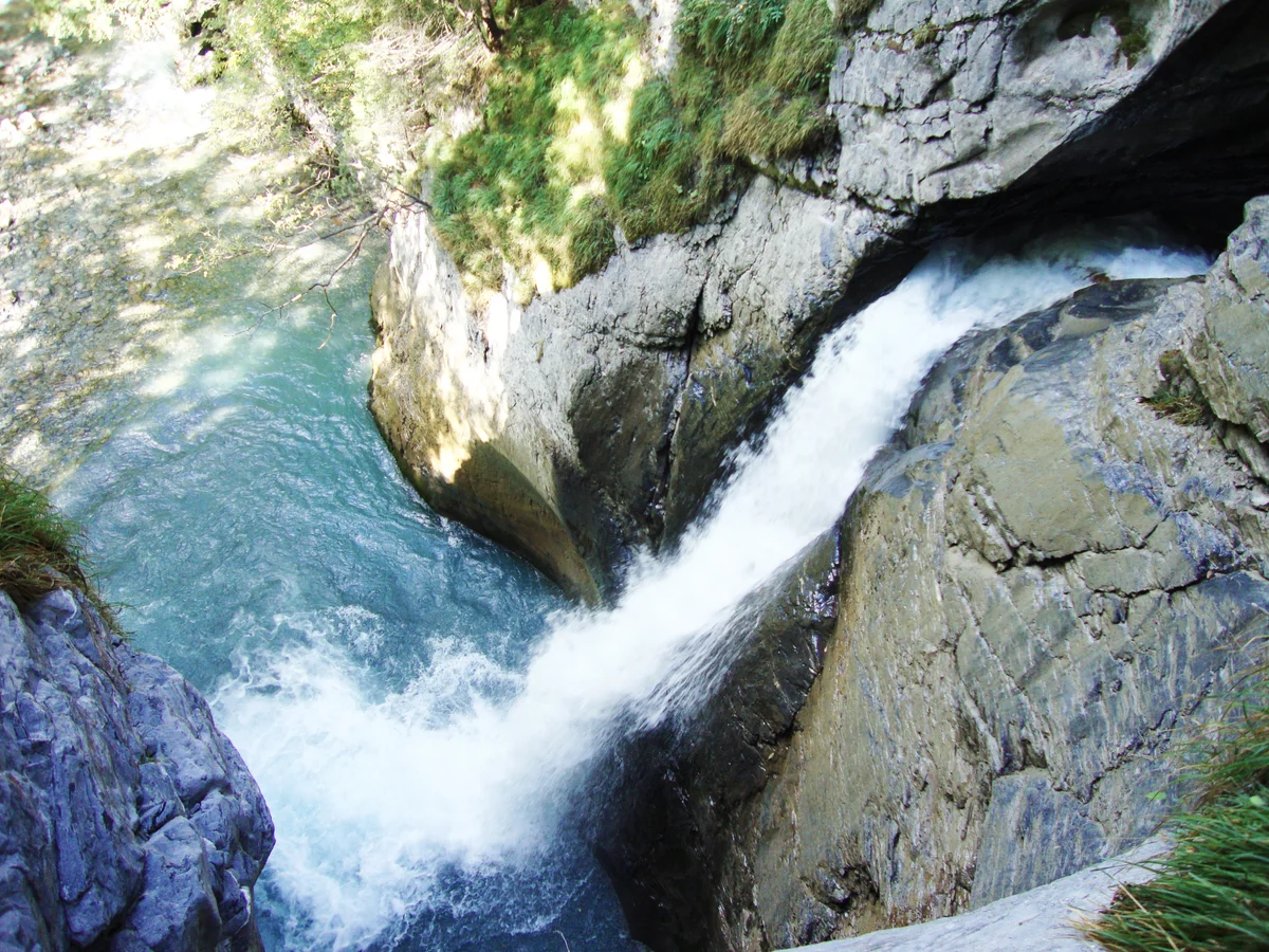 Türkisfarbenes Gletscherwasser schiesst durch die glatte Felsschlucht der Trümmelbachfälle bei Lauterbrunnen