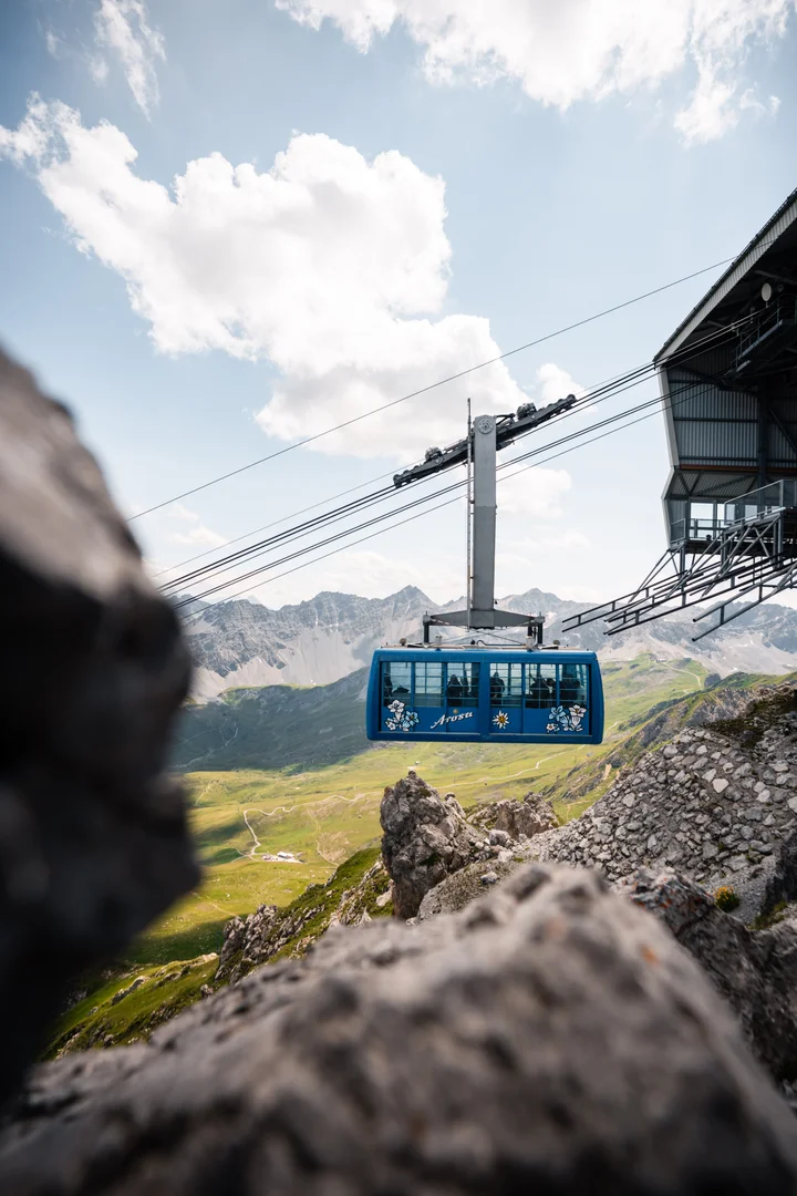 Blue gondola cabin of an Arosa mountain railway crossing the alpine landscape in summer