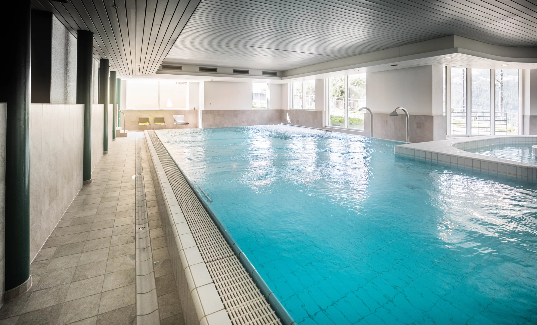 Indoor pool at the spa in Wengen at Victoria Lauberhorn, with a lap pool, a smaller spa pool and daylight through full height windows