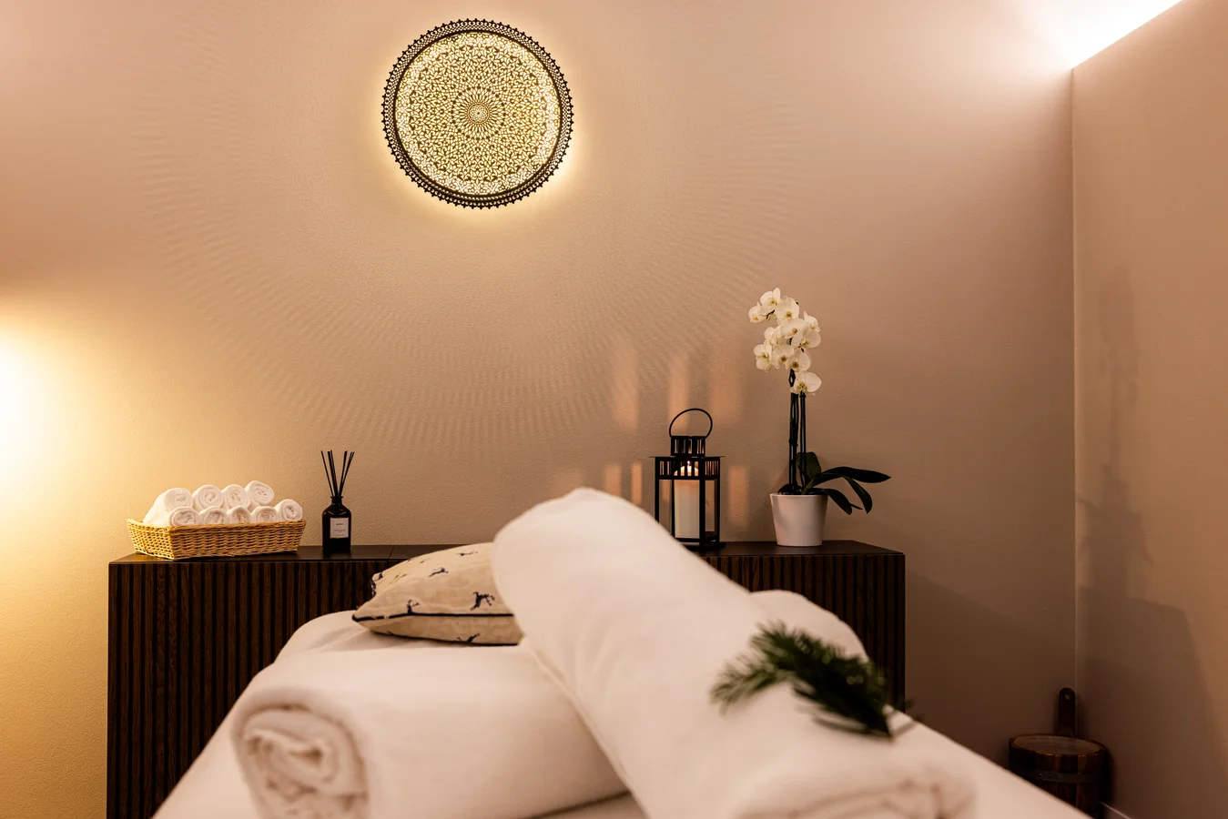 Treatment room at Altein, Arosa, prepared with a massage table, rolled towels, an orchid and soft lamplight