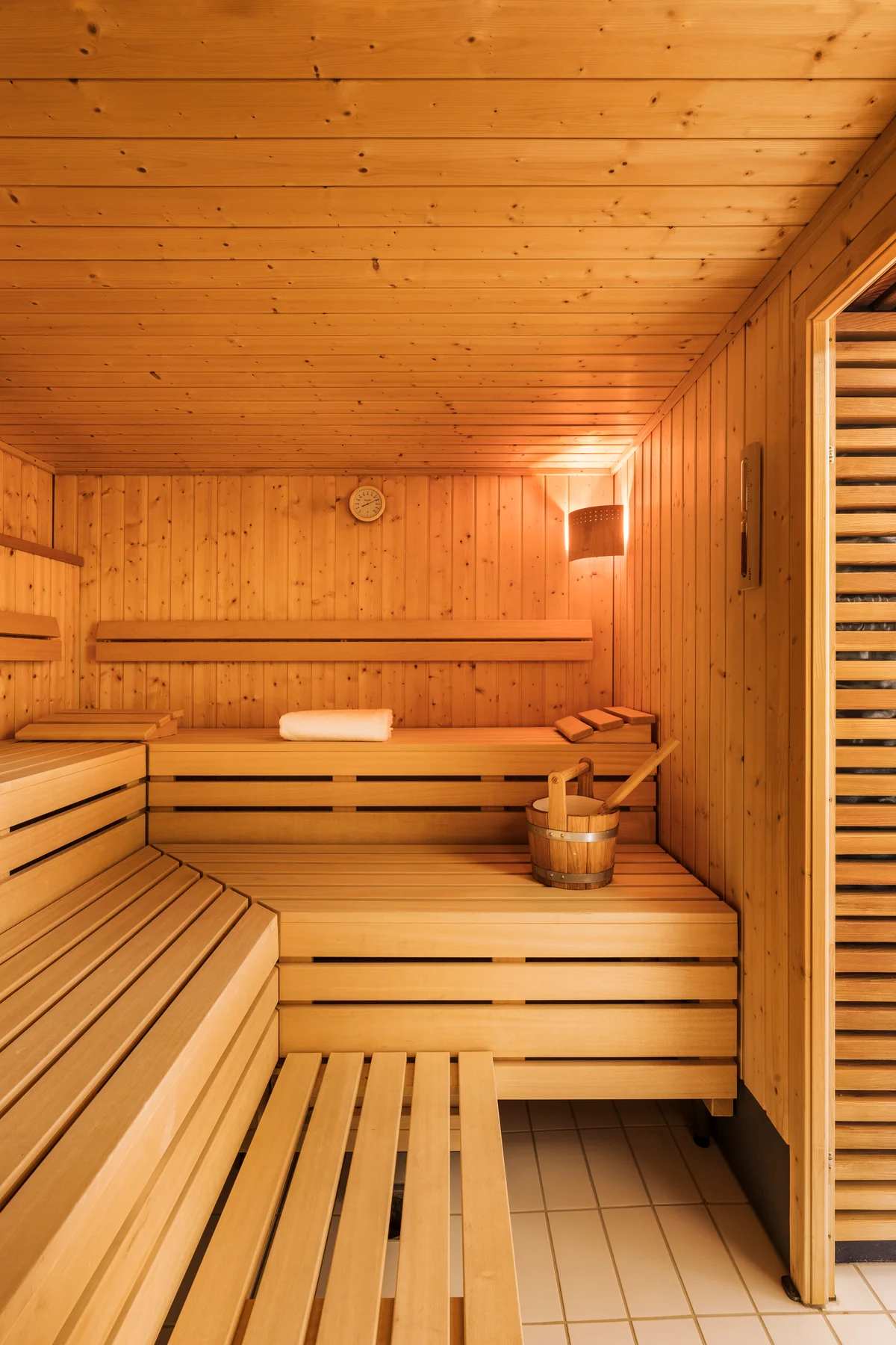 Wood panelled sauna at Altein, Arosa, with tiered benches and a wooden bucket and ladle