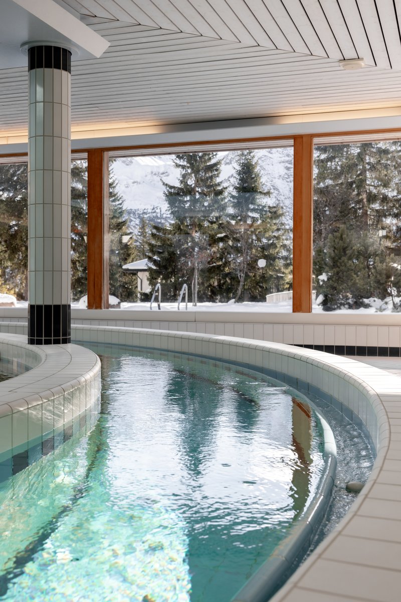 Indoor pool at Altein, Arosa, with a bubble area and windows onto snowy pine trees