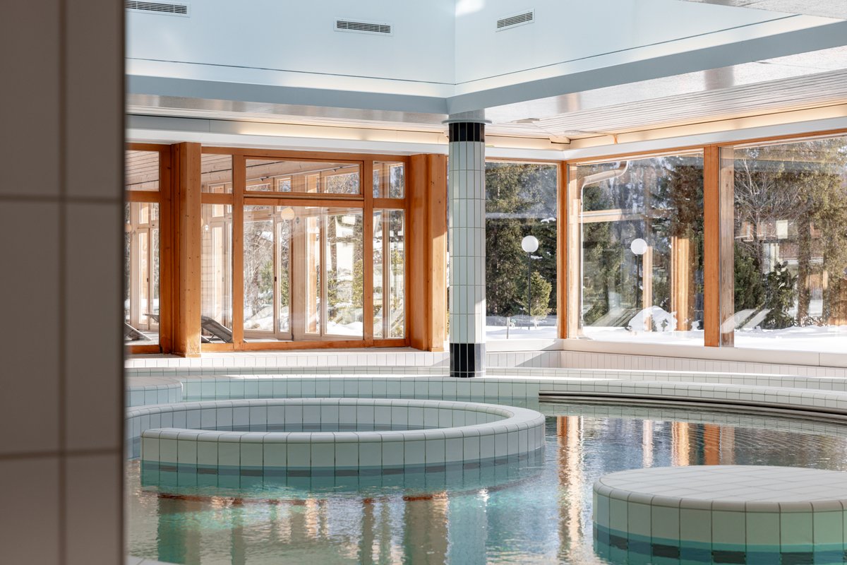 Piscina coperta dell'Altein, Arosa, con zona a bolle e finestre sugli abeti innevati