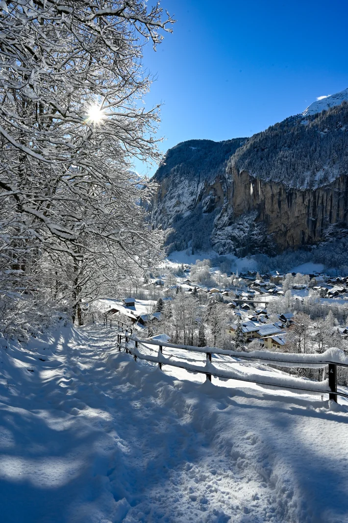 Verschneiter Weg oberhalb des Dorfes Lauterbrunnen unter den Felswänden, über die der Staubbachfall stürzt