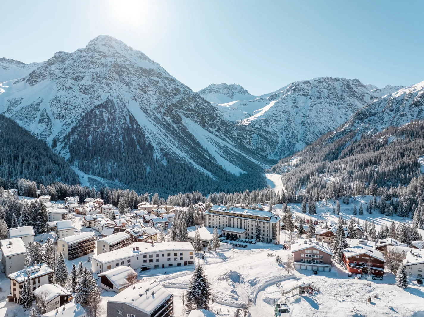 Verschneites Dorf Arosa mit Chalets und Hotels unter den Bergen im Winter