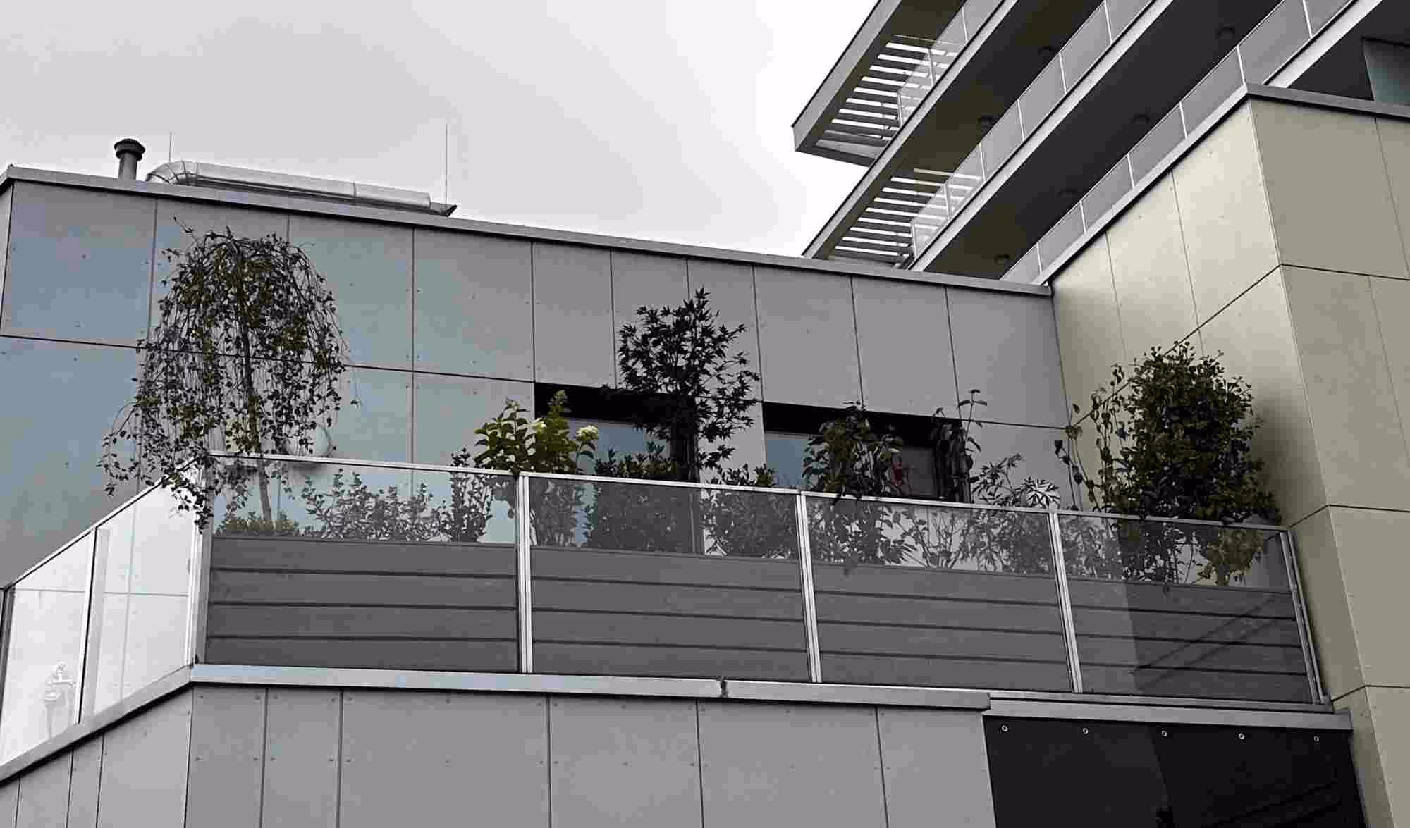 Großzügige Terrasse mit Pflanzkübeln, Sitzbank und stilvoll integrierter Begrünung am Geländer