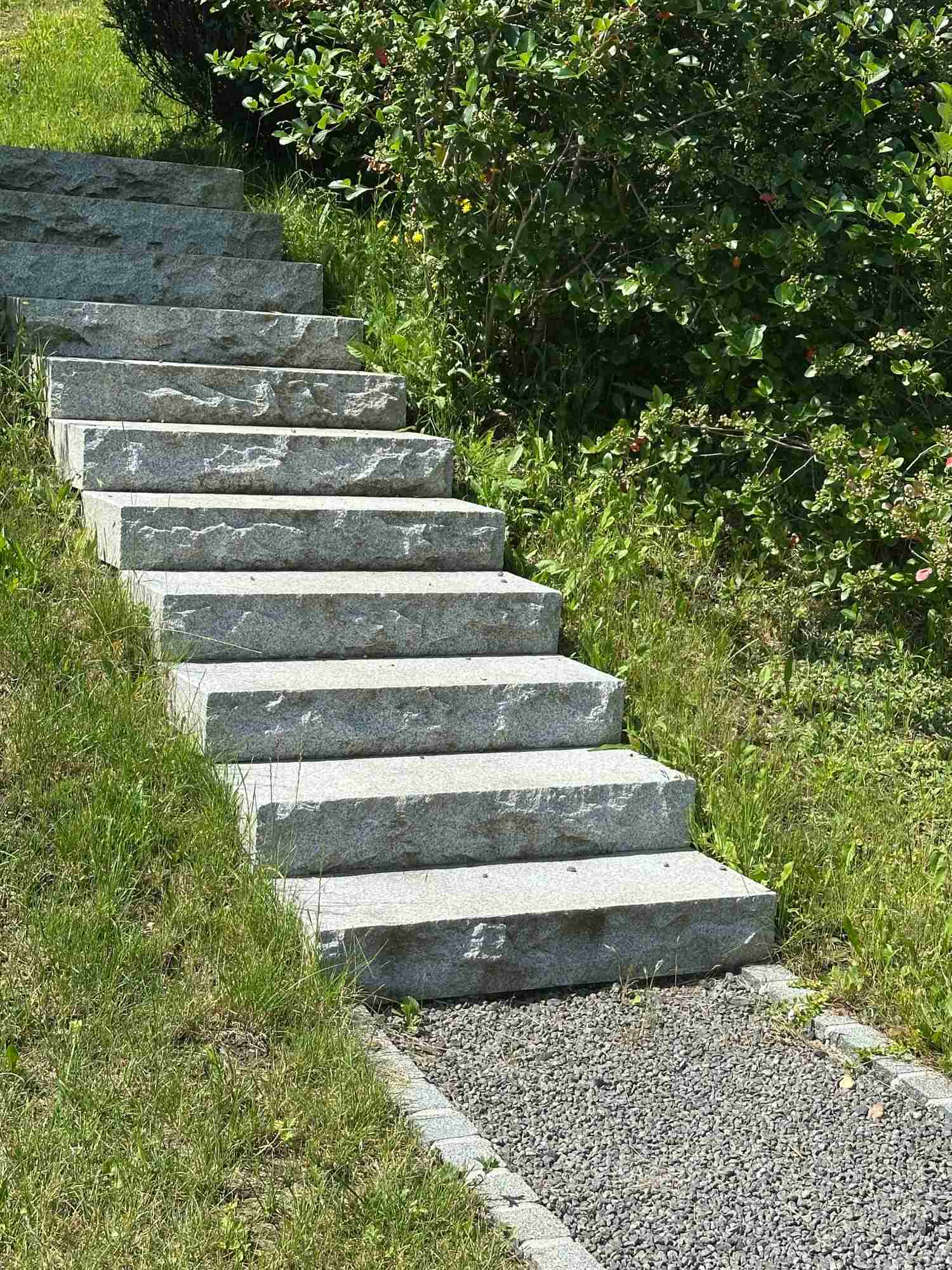 Treppenanlage im Garten aus großen Granitplatten inmitten von Grünfläche