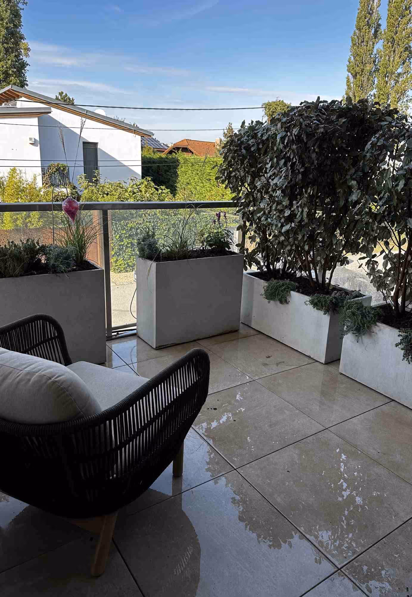 Stylischer Stadtbalkon mit Pflanzkübeln nach Maß und Lounge-Sessel