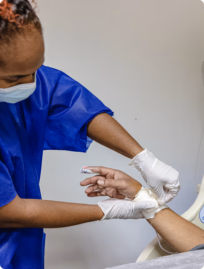 A nurse in blue scrubs prepares a patient’s arm for an injection.