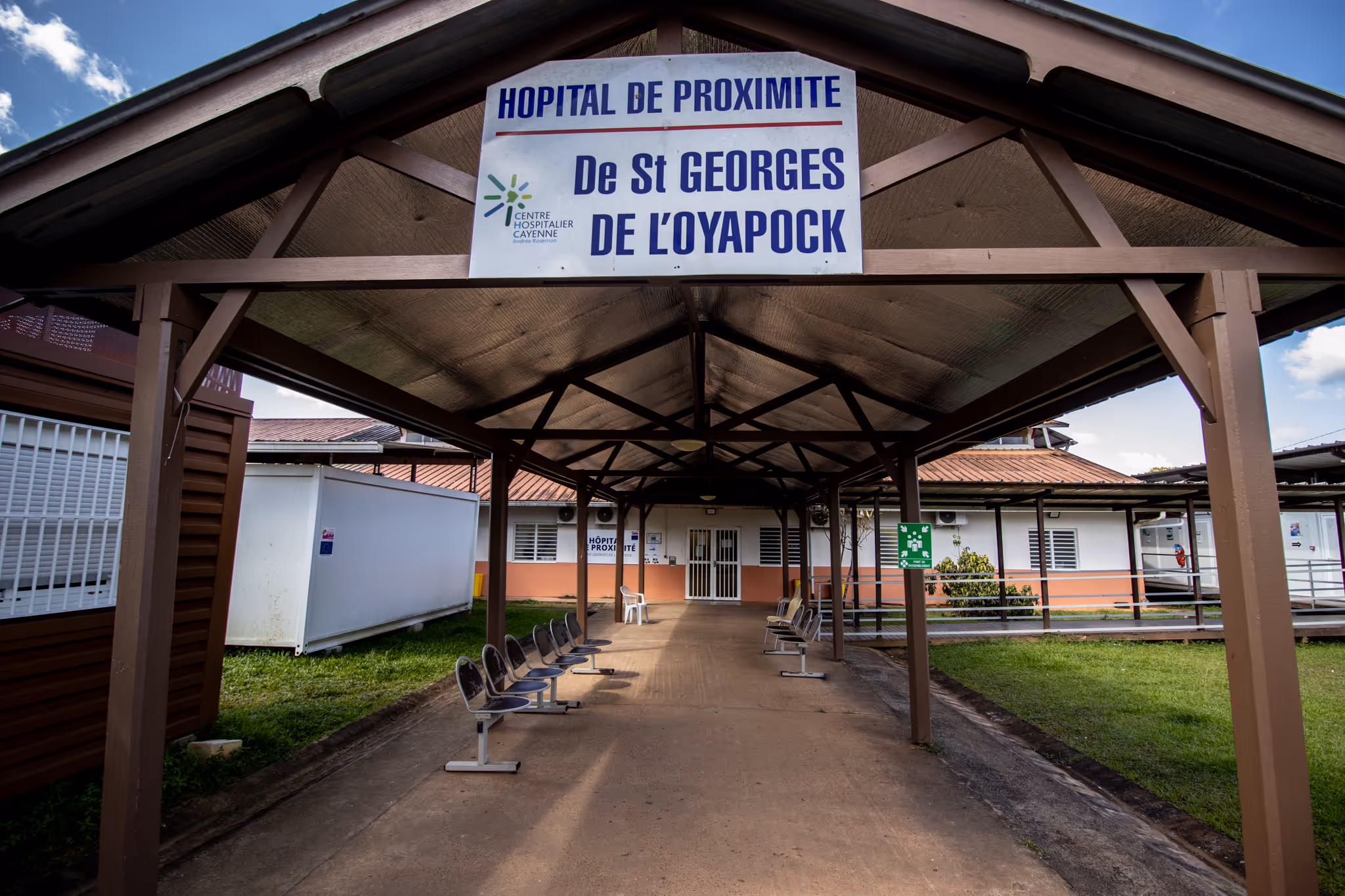 Entrance to a hospital with seating outside under a covered walkway.