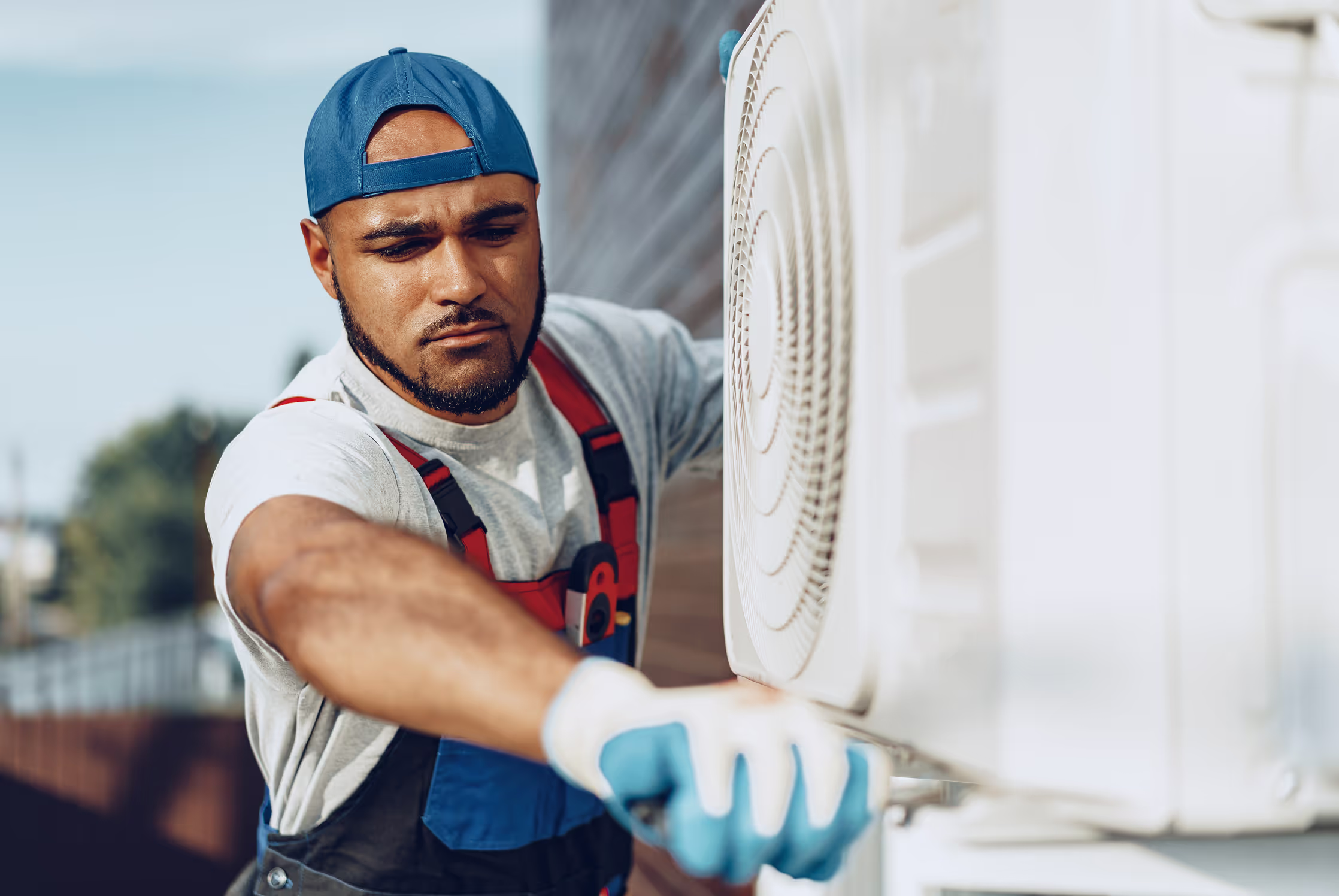 Technician repairing an outdoor AC unit next to a house.