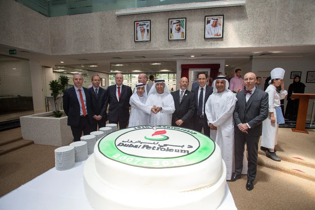 Executives cutting a celebration cake with their team