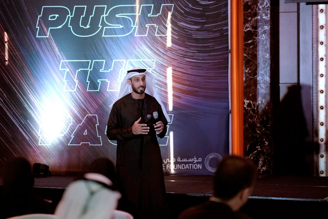 Speaker on stage in front of a lit backdrop