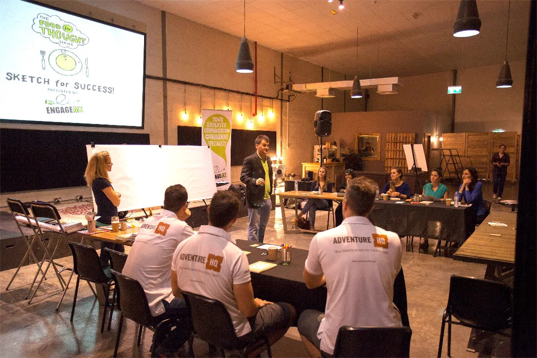 Teams at tables during a workshop in a warmly lit venue