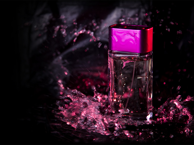 Pink perfume bottle with a liquid splash on black