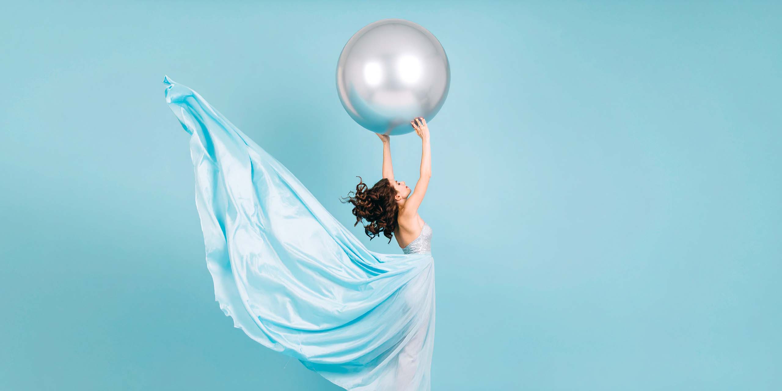 Frau mit Ballon den sie in die Luft hält.