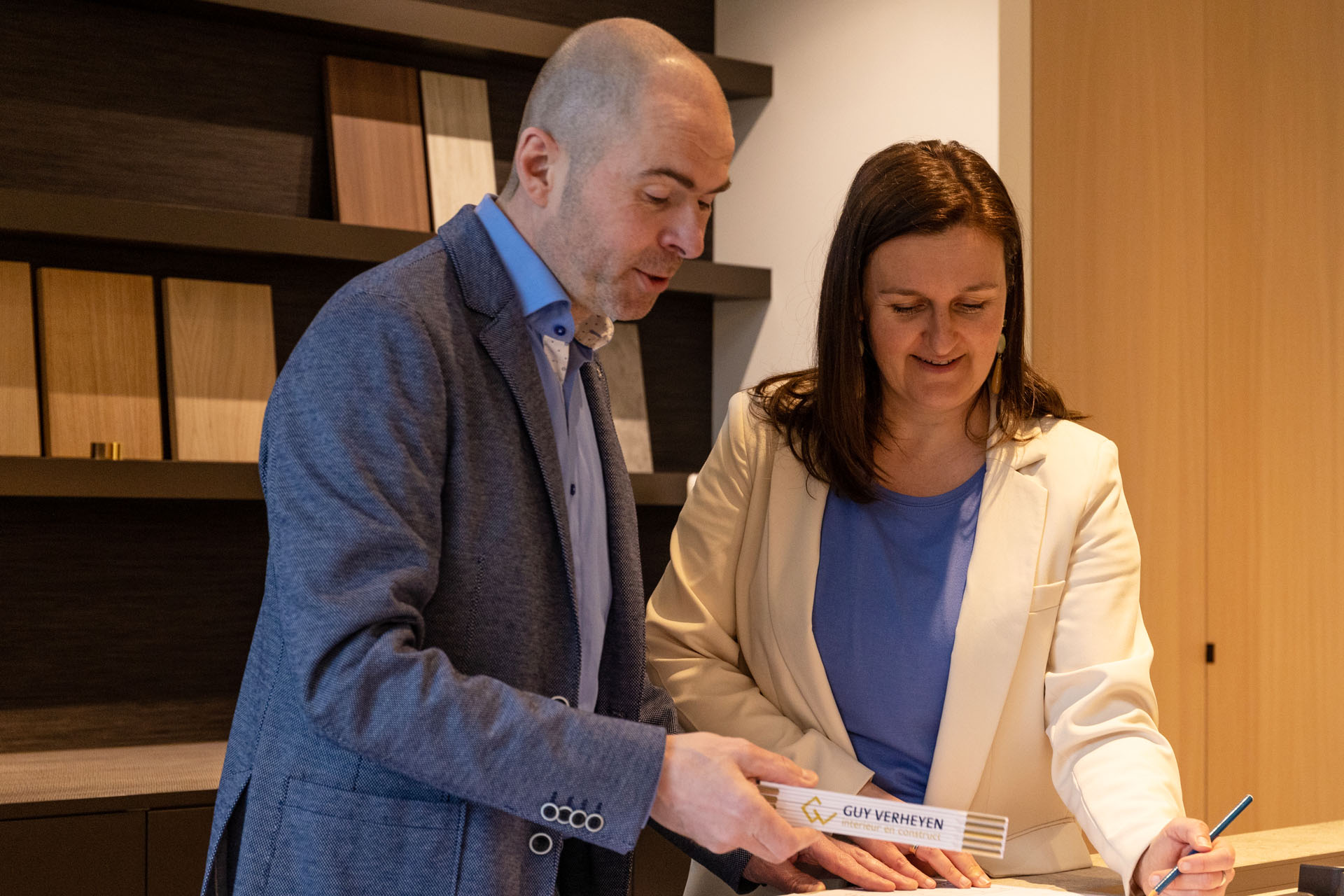 Man and woman reviewing building samples and documents together in an interior design setting.
