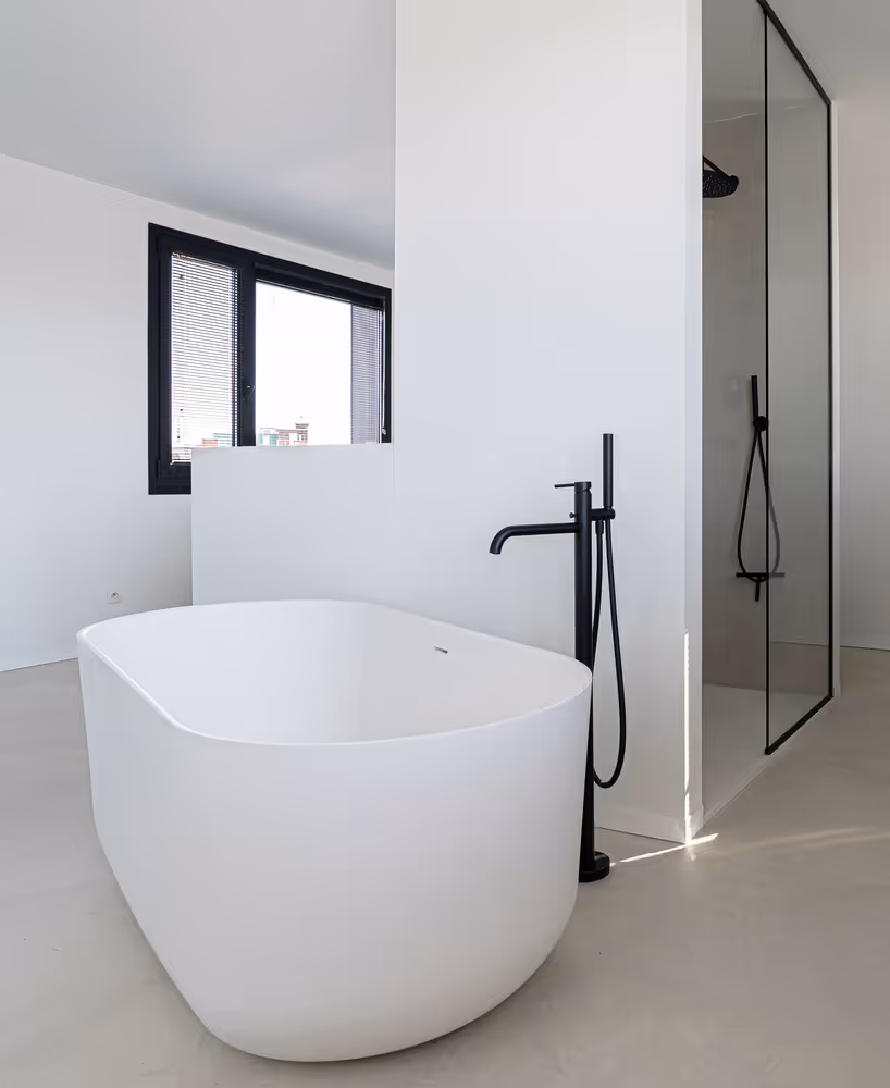 Modern bathroom with a freestanding white bathtub, black floor-mounted faucet, and a walk-in shower with black frame glass door.