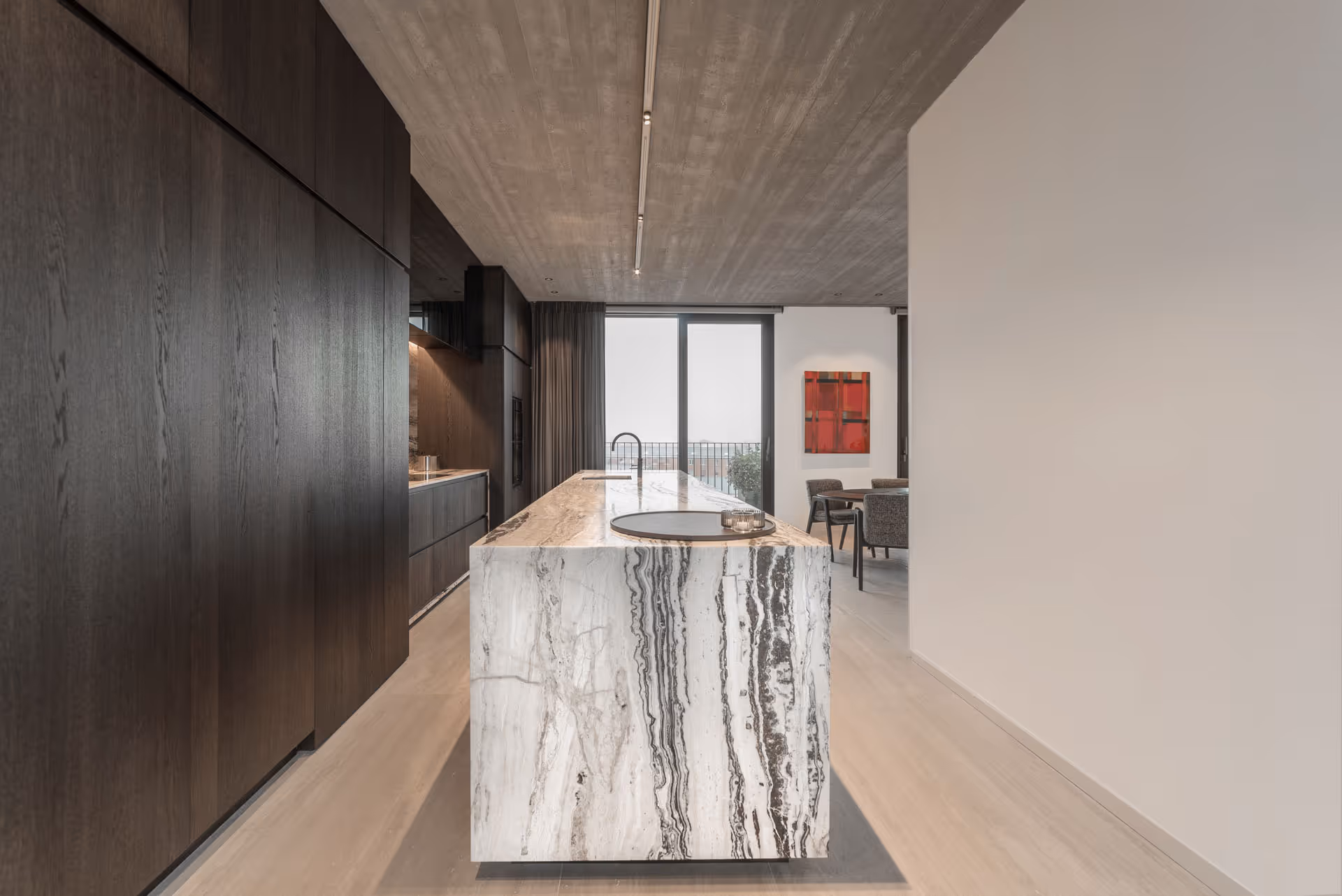 Moderne keuken met marmeren kookeiland en donkere houten kasten in een strak interieur.