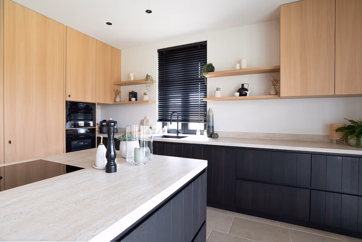 Eigentijdse keuken met zwarte onderkasten, lichte werkbladen en wandkasten in hout, aangevuld met open houten planken en zwarte jaloezieën.