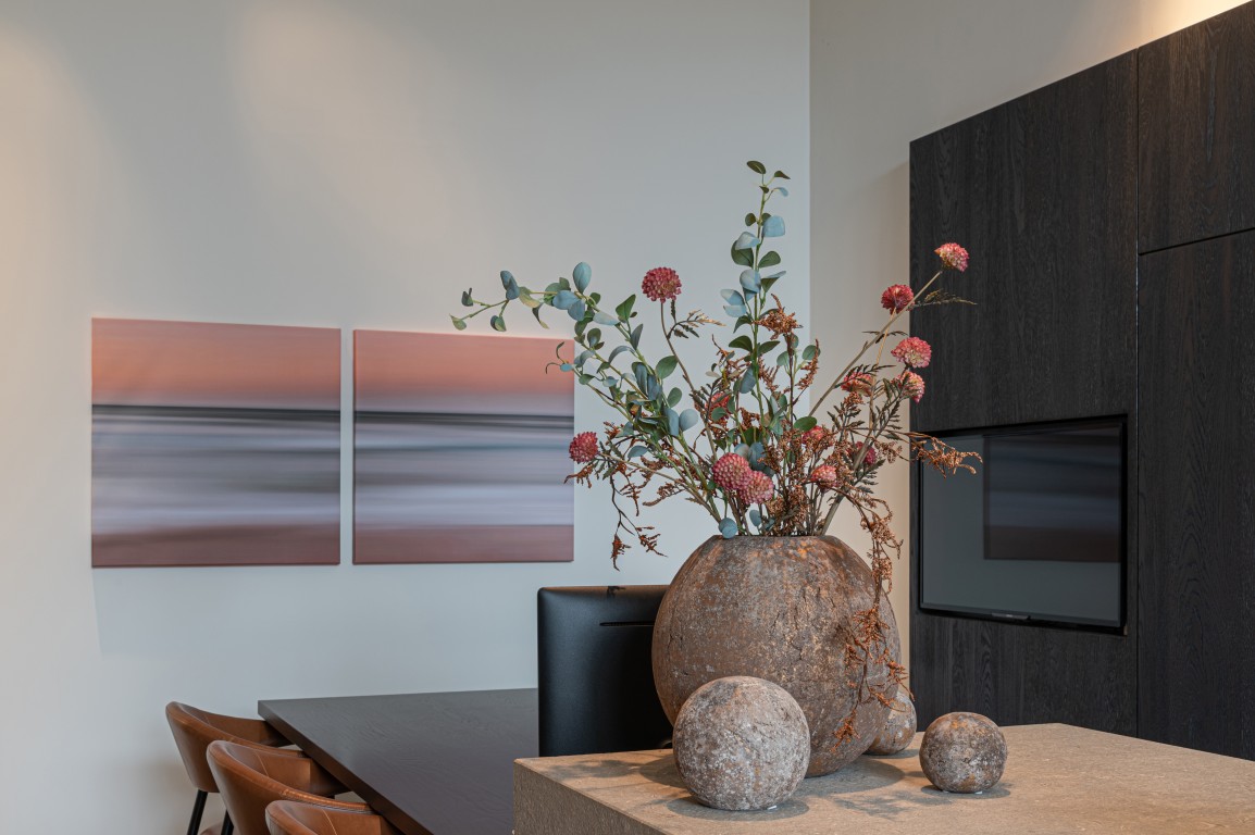 Eethoek met donkere kastenwand en vaas met droogbloemen