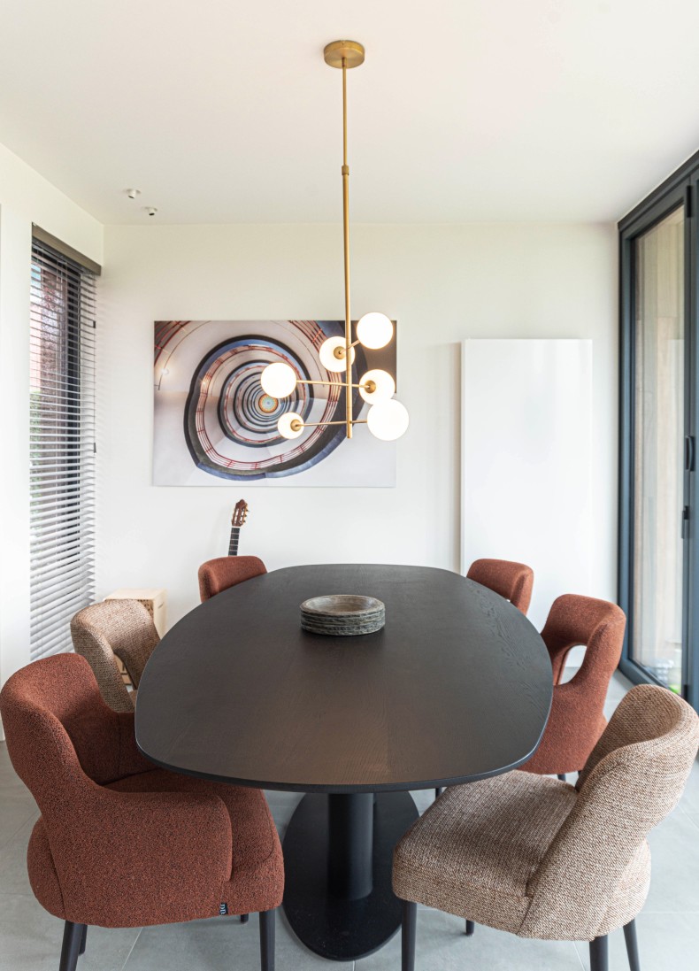 Ovale zwarte eettafel met roestbruine stoelen en hanglamp