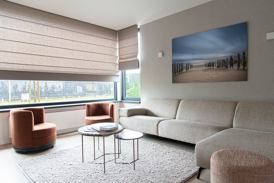 Woonkamer met beige hoeksofa en roestbruine fauteuils
