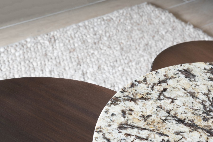 Detail van houten en marmeren salontafels op wit tapijt
